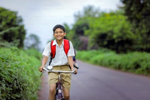 Lindo niño indio de escuela que va a la escuela en bicicleta