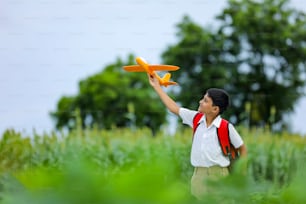 Sogni di volo! Bambino indiano che gioca con l'aeroplano giocattolo al campo verde