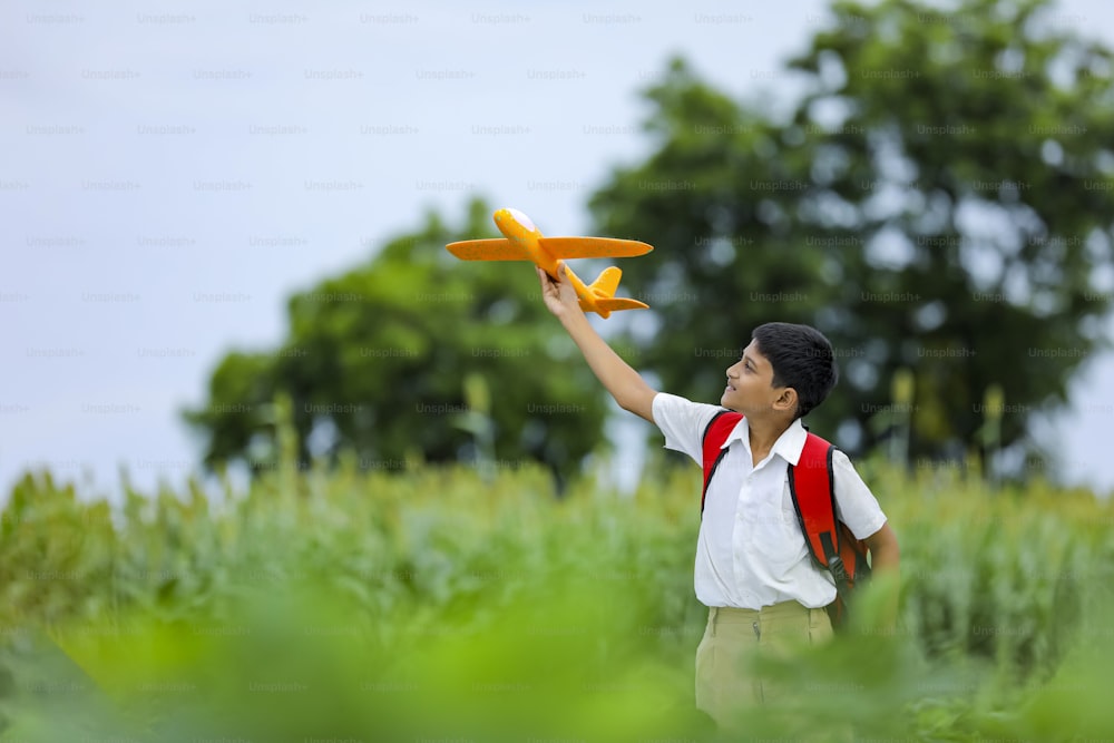 Sogni di volo! Bambino indiano che gioca con l'aeroplano giocattolo al campo verde