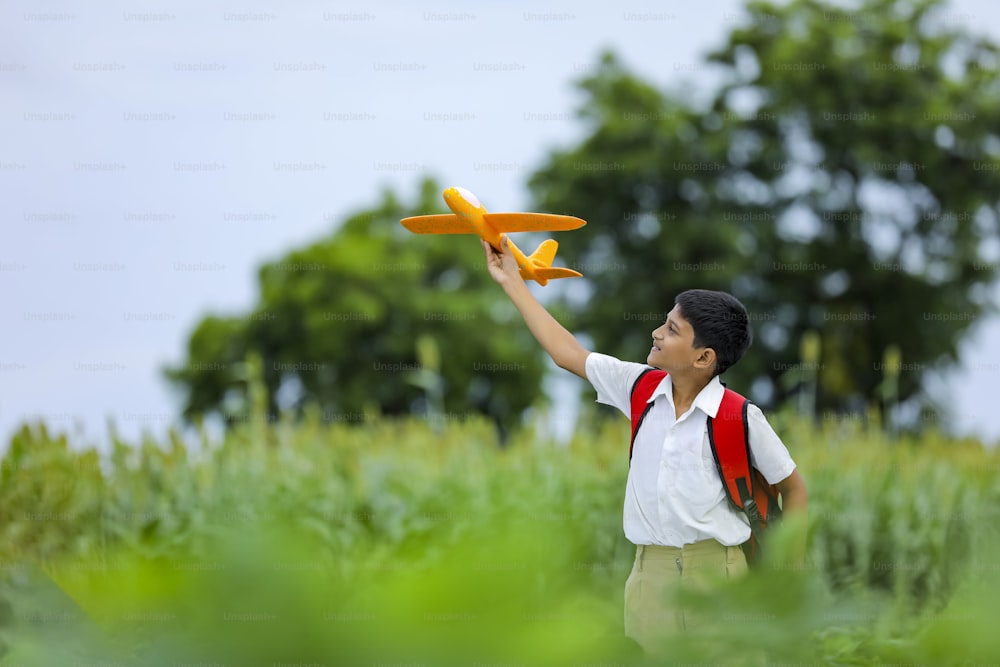 飛行の夢!グリーンフィールドでおもちゃの飛行機で遊ぶインドの子ども