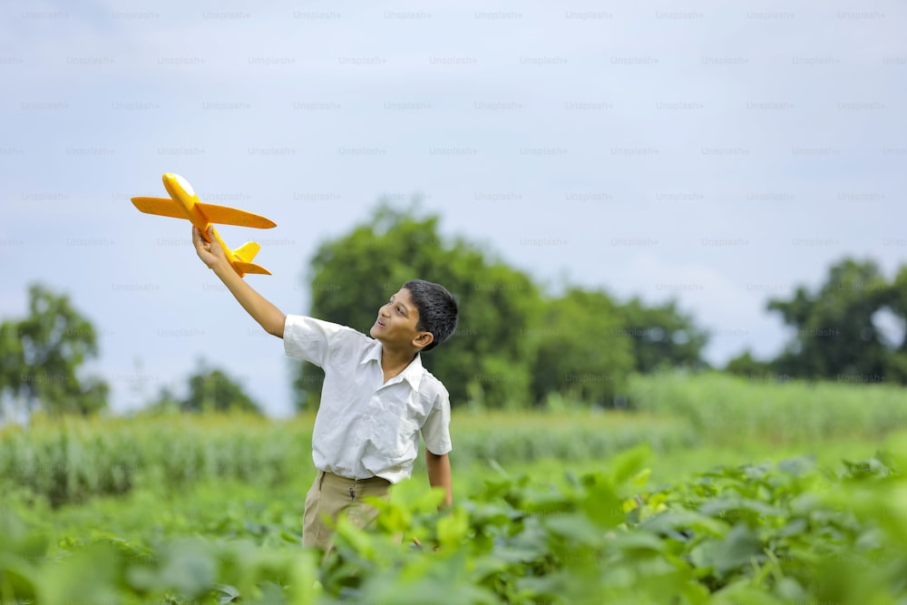 ¡Sueños de vuelo! Niño indio jugando con un avión de juguete en Green Field