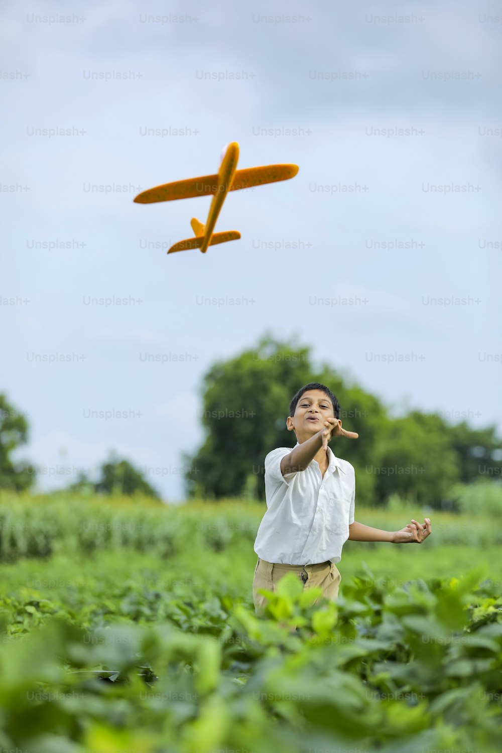Sogni di volo! Bambino indiano che gioca con l'aeroplano giocattolo al campo verde