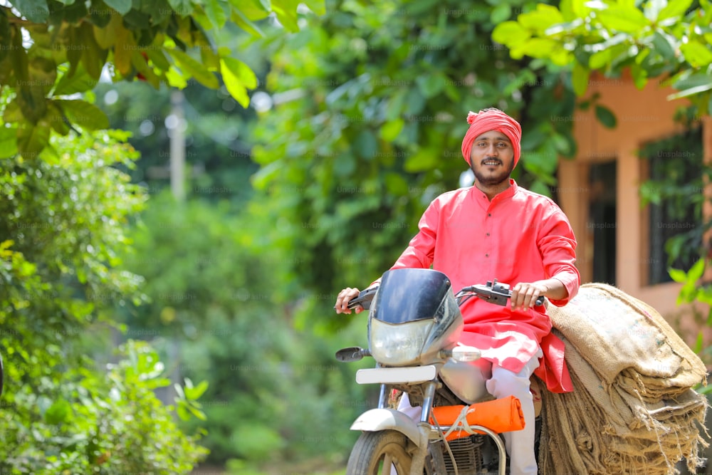 젊은 인도 농부가 오토바이에 굵은 베옷을 모은다