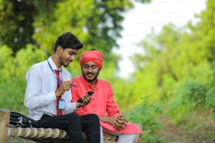 Junger indischer Banker diskutiert mit Farmer auf dem Feld.