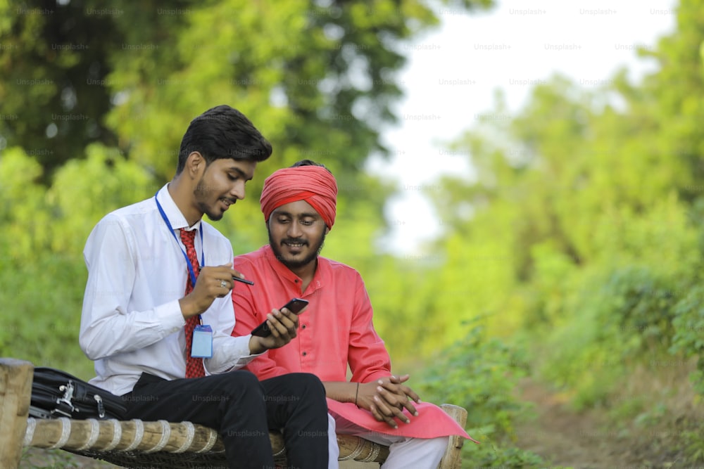 Joven banquero indio discute con un agricultor en el campo.