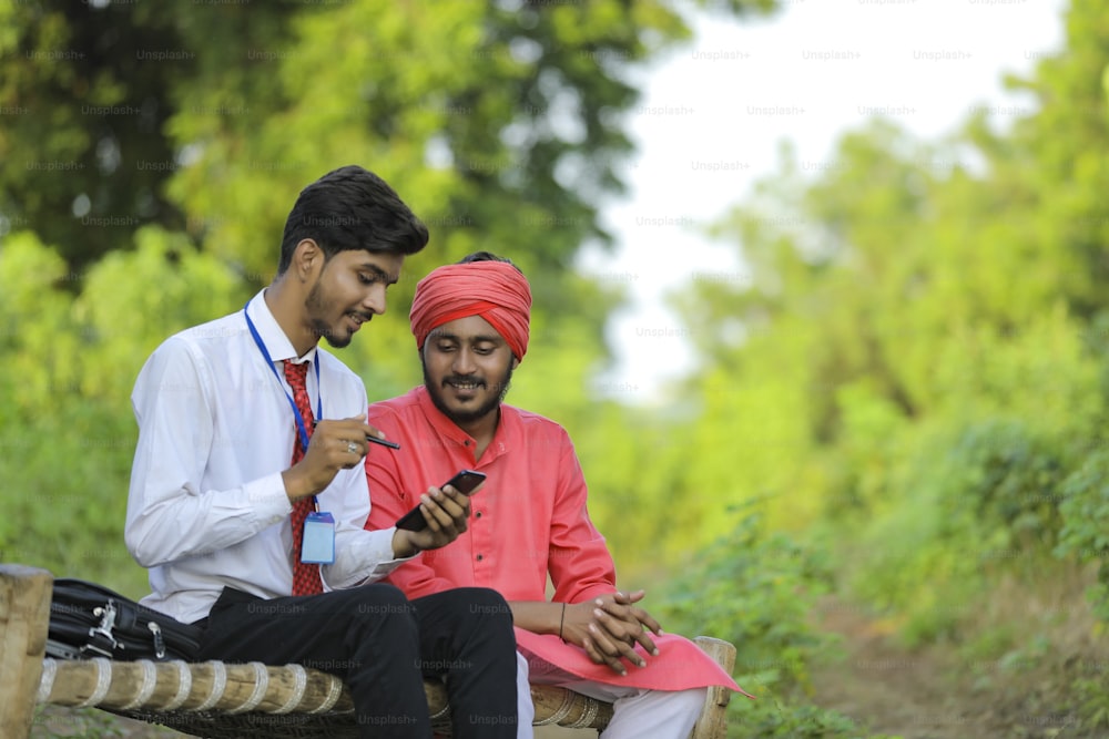 Young Indian banker discuss with farmer at field.