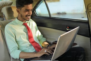 Young indian business man using laptop in side of car
