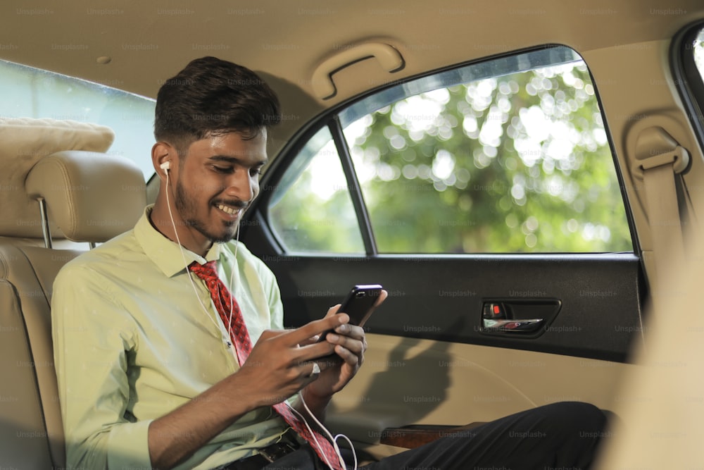 Homem indiano jovem ouvindo música no telefone móvel no carro
