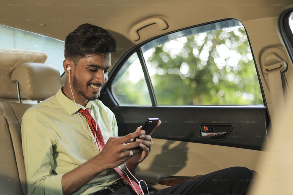 Young Indian man listening music on mobile phone in car