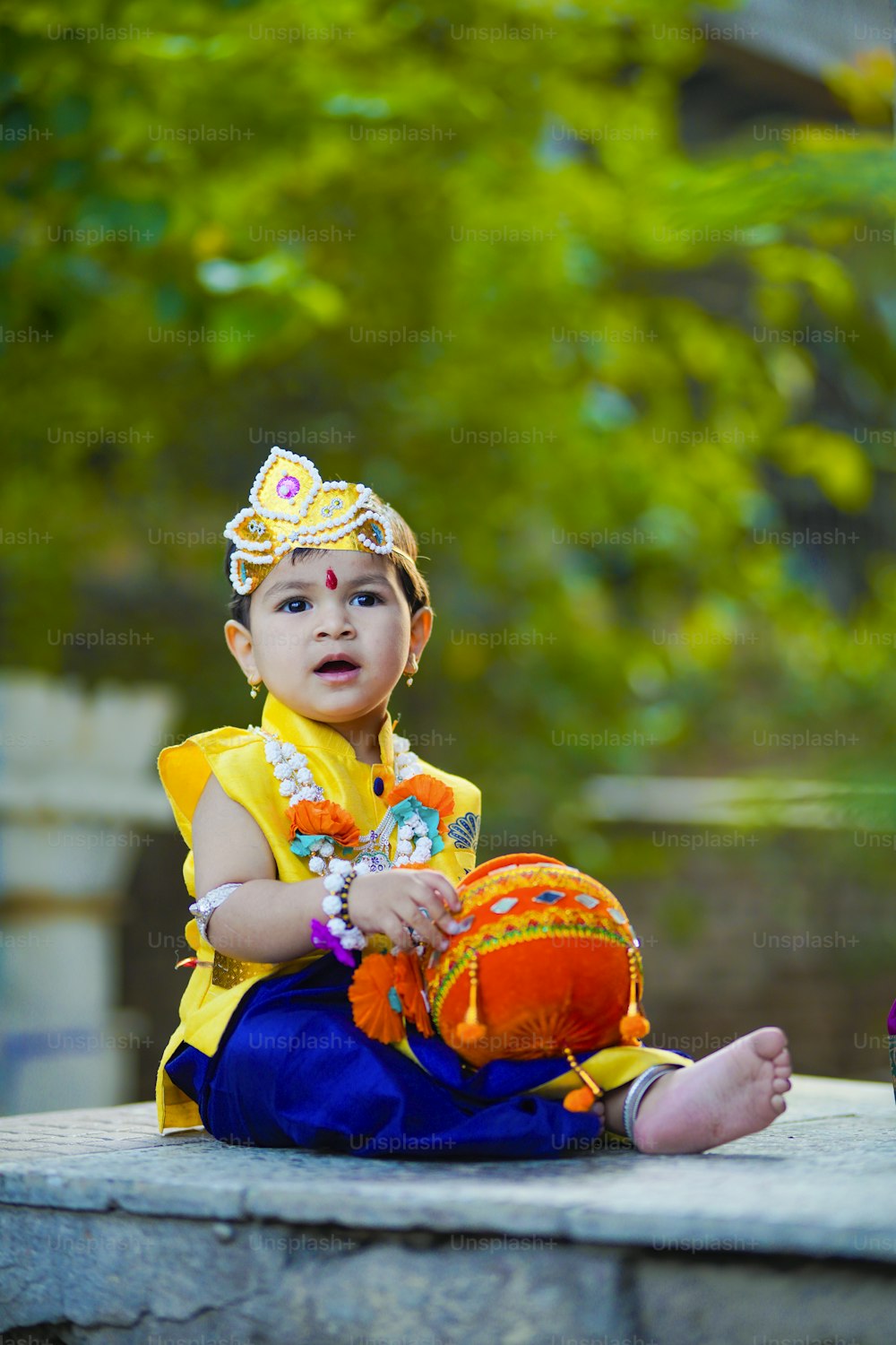 ダヒハンディの写真とカラフルな花でシュリクリシュナまたはカンハ/カンハイヤを装った小さなインドの少年を示す幸せなジャンマシュタミグリーティングカード。