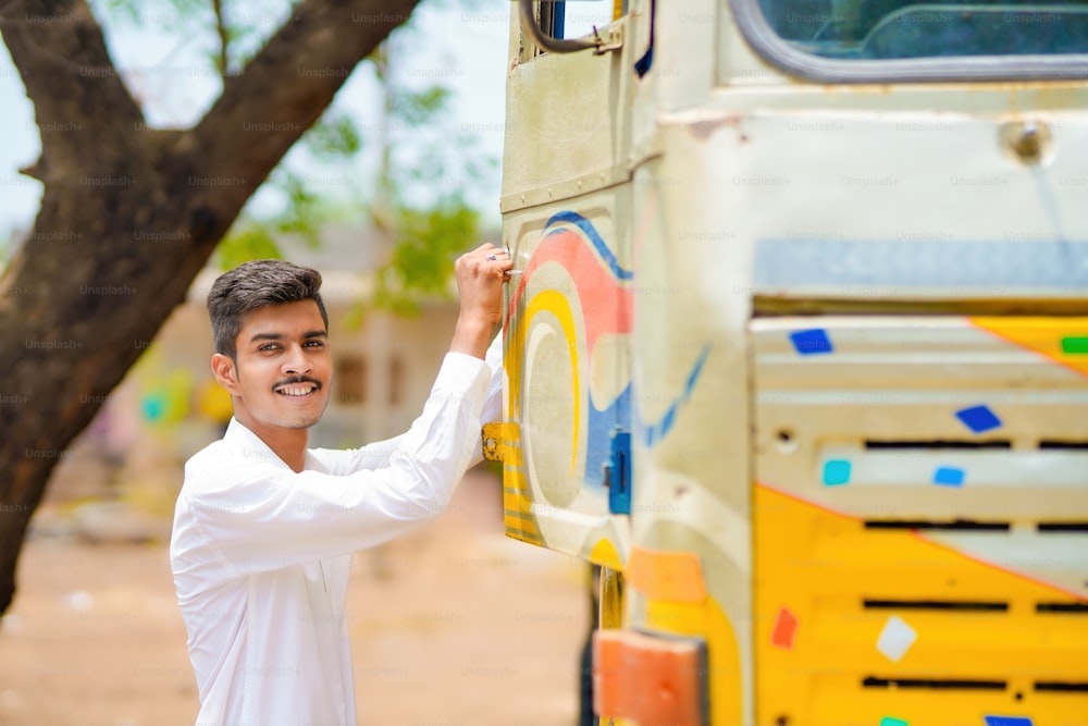 Joven hombre de negocios indio con su camión o camión de carga.