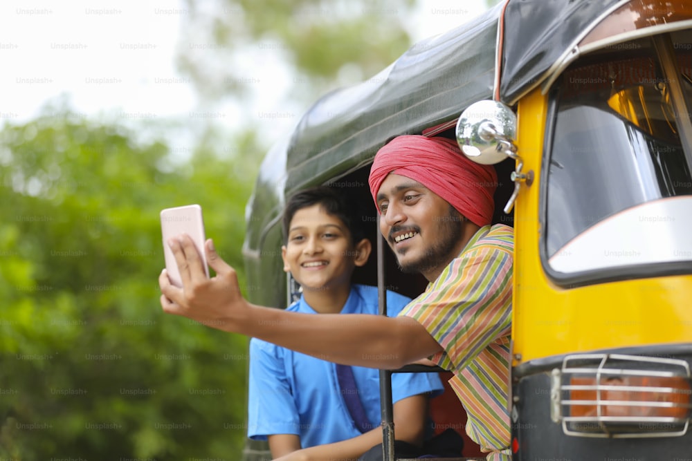 Un conducteur indien de rikshaw ou de tuk tuk prend un selfie avec son écolier