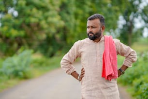 Young indian farmer standing in cotton agriculture field.