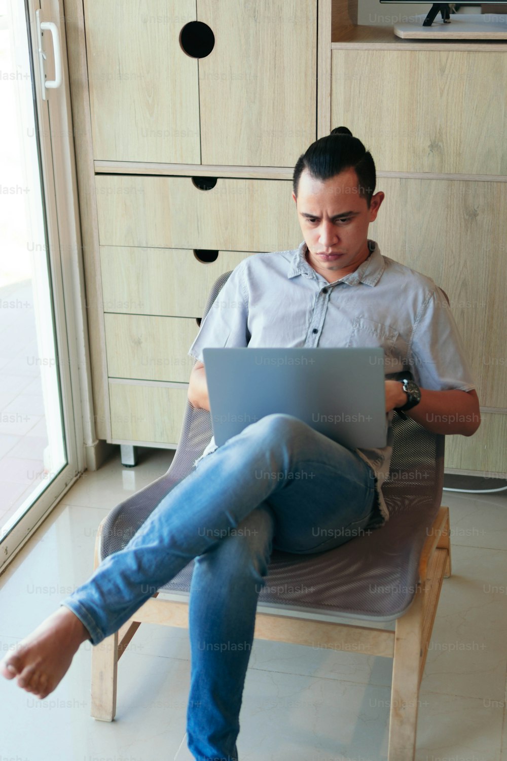 Hispanic Man sitting in the living room of his house, using a laptop to work from home