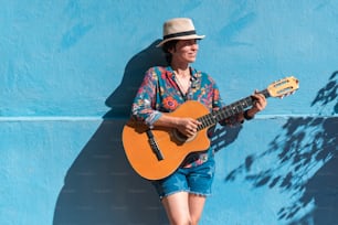 Joven músico femenino con una guitarra en una calle