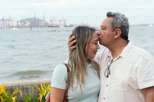 Mann küsst seine Frau unter freiem Himmel auf die Stirn