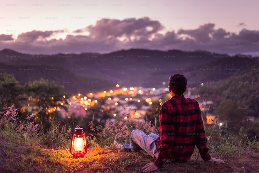若者は自由に感じ、人生を楽しみ、夕暮れの空で街の明かりを見ています。 灯油ランプが点灯しています。