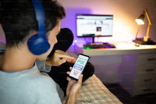 Jeune homme achetant en ligne à la maison et payant via PIX.  PIX est un nouveau système de paiement électronique au Brésil.