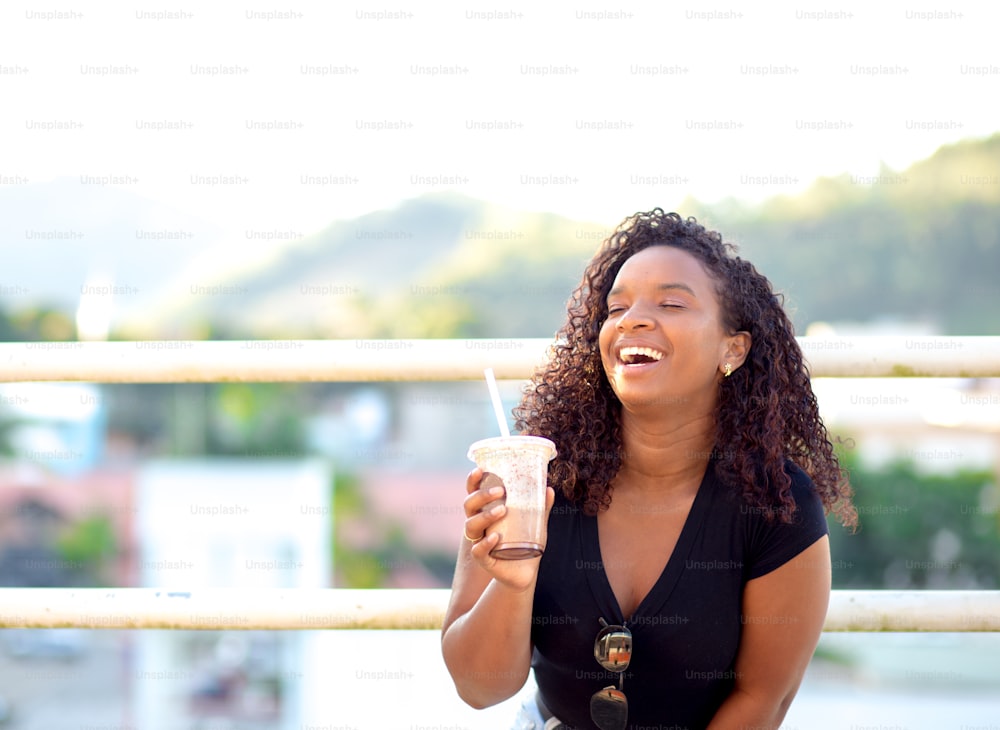 Happy young woman drinking a milkshake on the street.