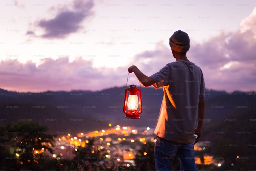 灯油ランプをつけて自由に感じ、夕暮れの空で風景を眺める人。