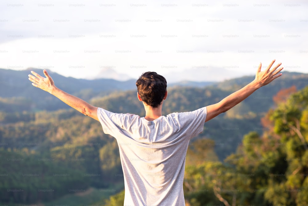 Young man with his arms raised with mountains in the background. Freedom, success and happiness concept.