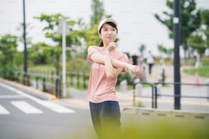 Jeune femme asiatique portant des vêtements de sport et faisant de l’exercice dans le parc