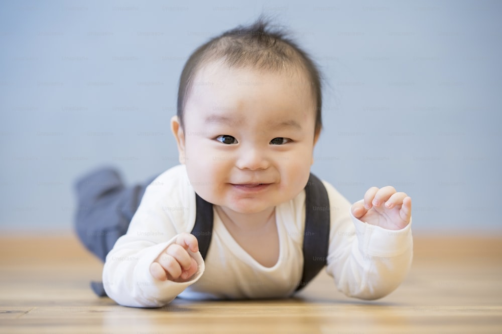Bebê japonês rastejando no chão de madeira no quarto