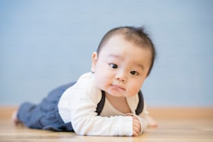 방의 나무 바닥에서 기어 다니는 일본 아기