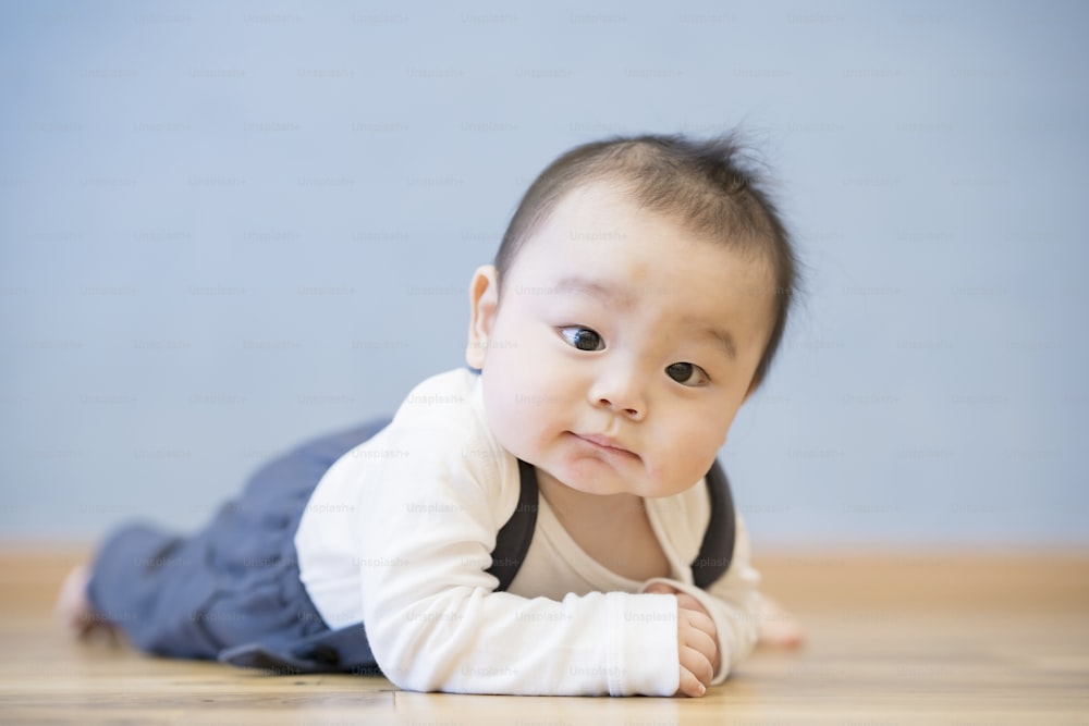 방의 나무 바닥에서 기어 다니는 일본 아기