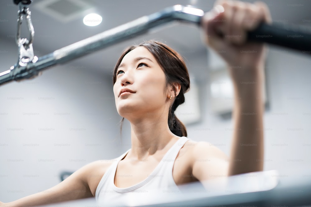 Asiatische junge Frau trainiert im Fitnessstudio