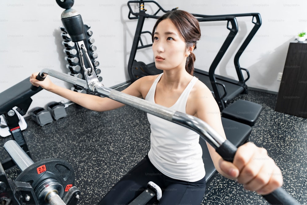 Asiatische junge Frau trainiert im Fitnessstudio