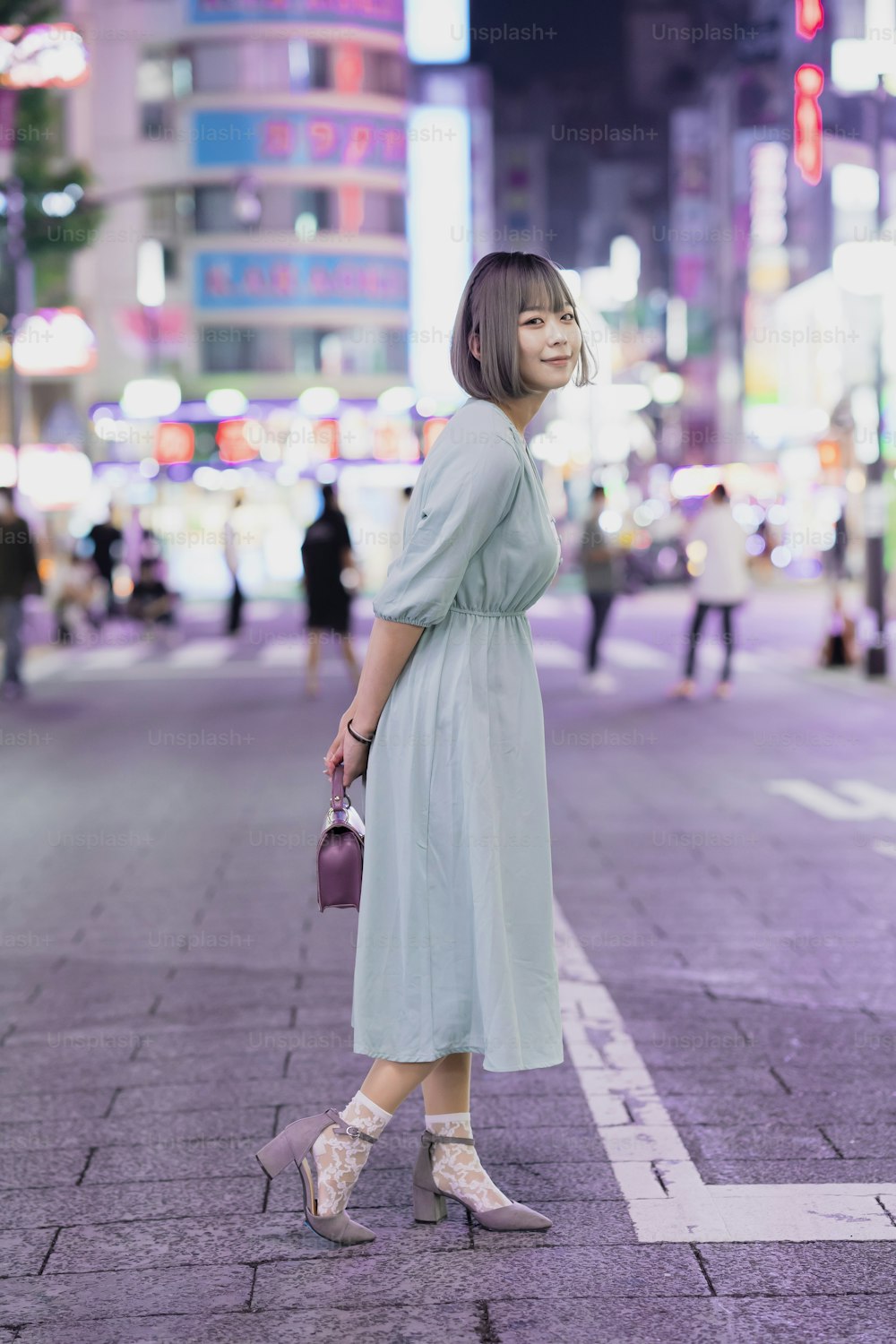 Young woman posing in the glowing cityscape of Tokyo at night