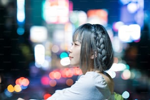 Mujer joven posando en el resplandeciente paisaje urbano de Tokio por la noche