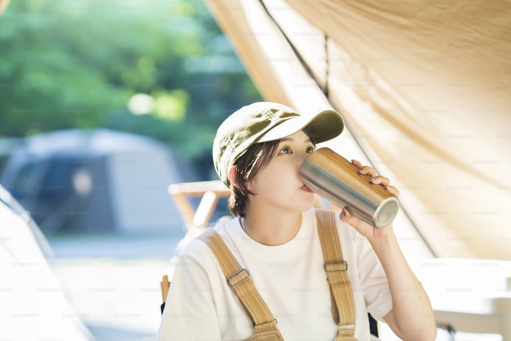 Imagen del campamento en solitario - Mujer joven bebiendo alcohol