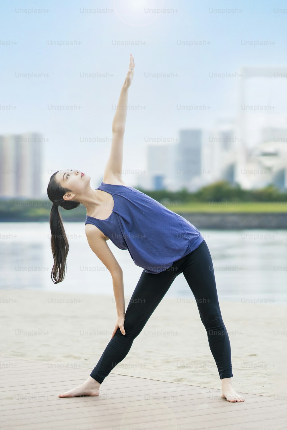 Asian young woman doing yoga on the beach in the city