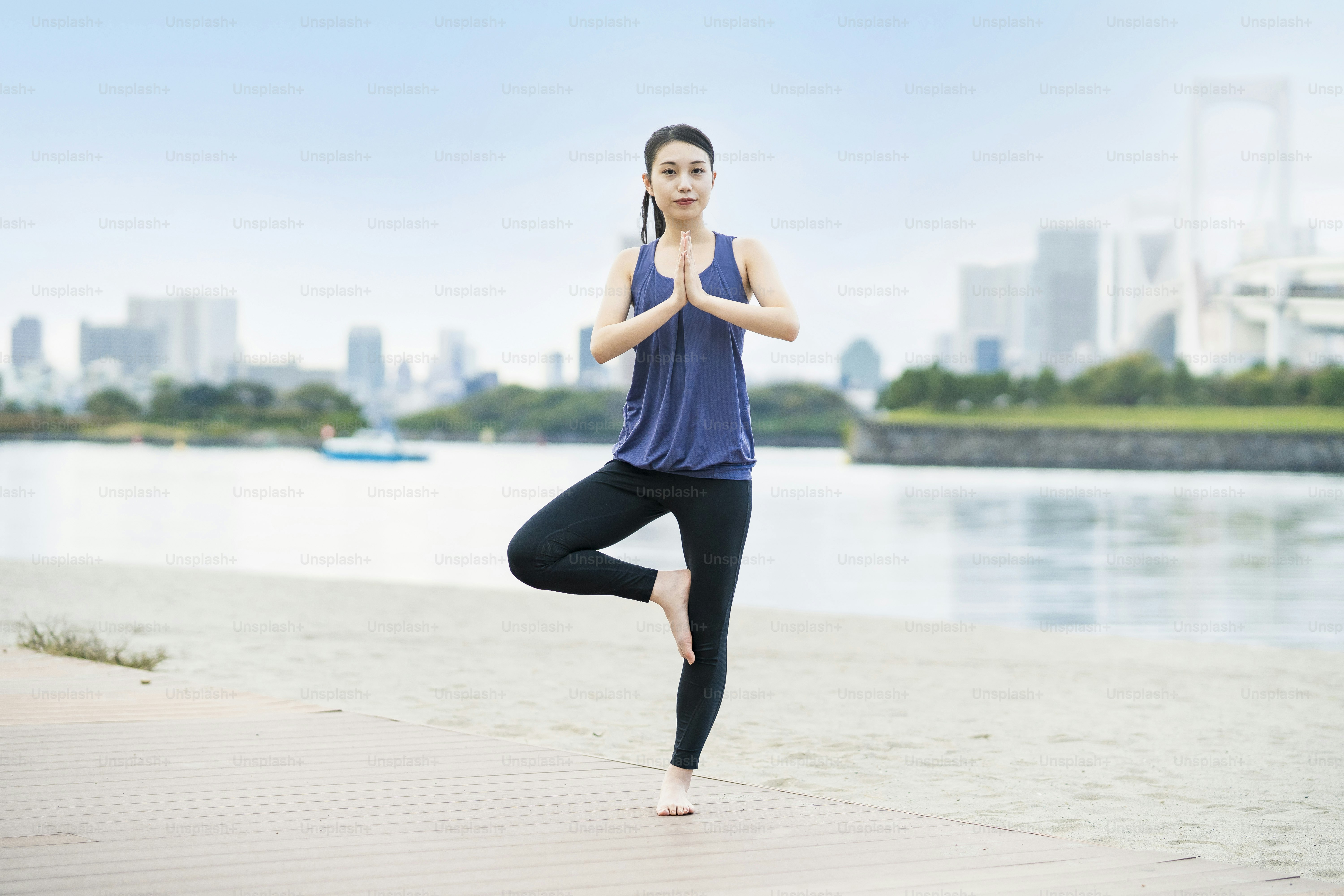 Asian young woman doing yoga on the beach in the city