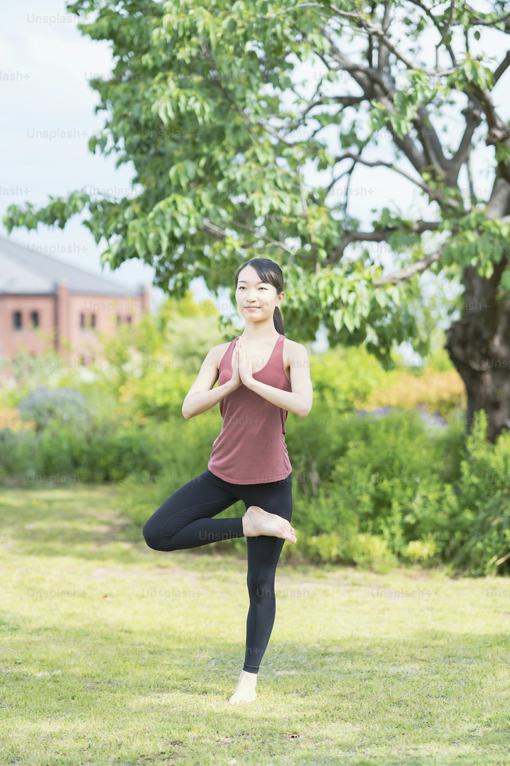 Mulher nova que faz yoga em um parque verde no dia fino