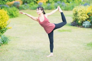 Young woman doing yoga in a green park on fine day