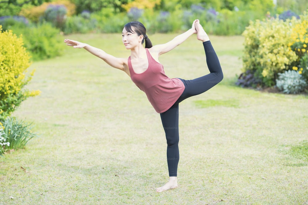 Young woman doing yoga in a green park on fine day