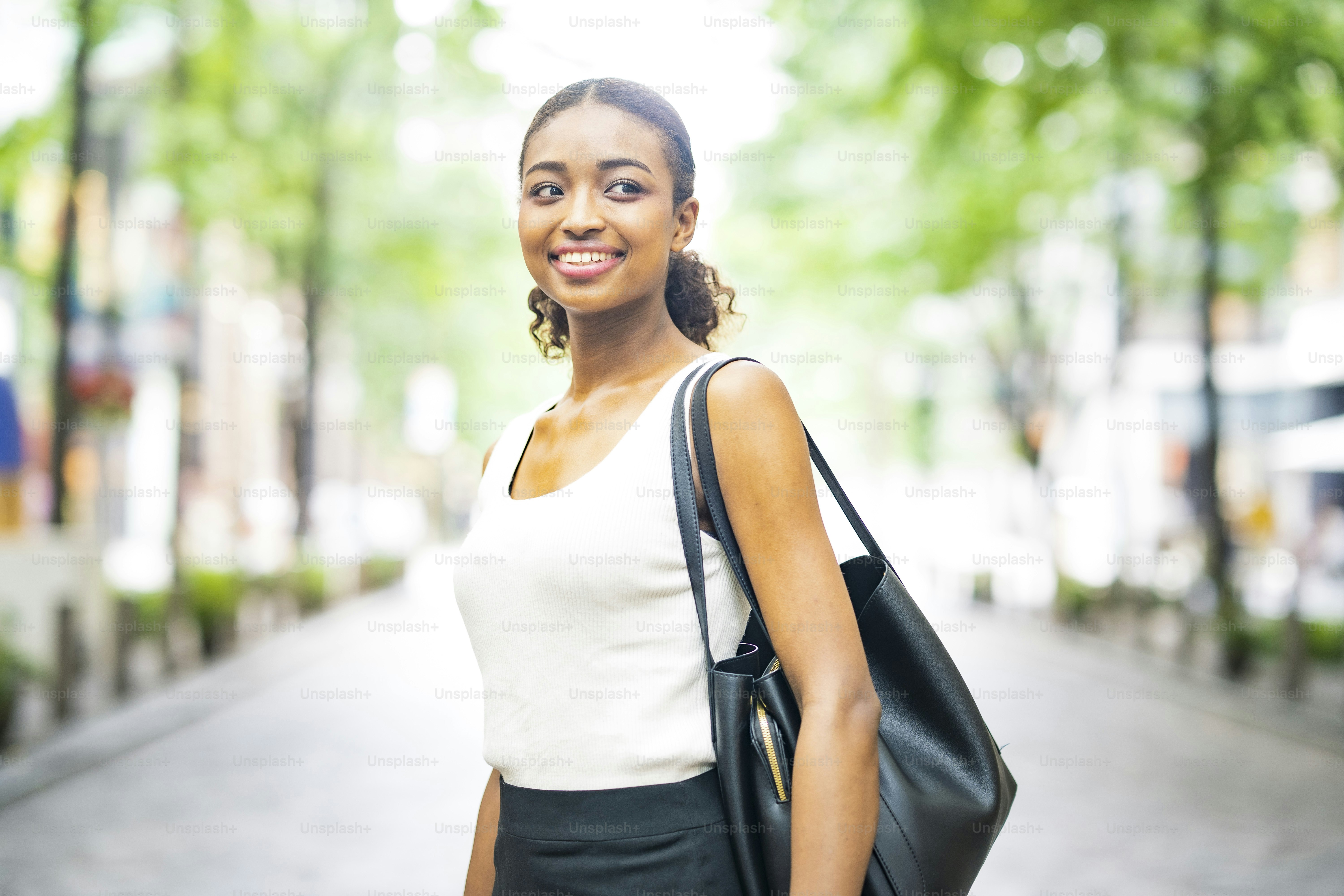 Jeune femme d’affaires en hauts blancs sans manches dans une ville verte