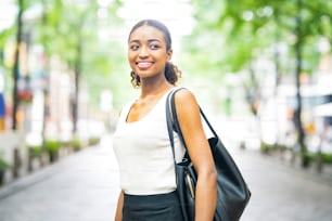 Young business woman in sleeveless white tops in a green city