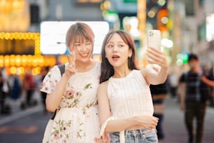 Mujeres jóvenes tomándose selfies en el centro de la ciudad