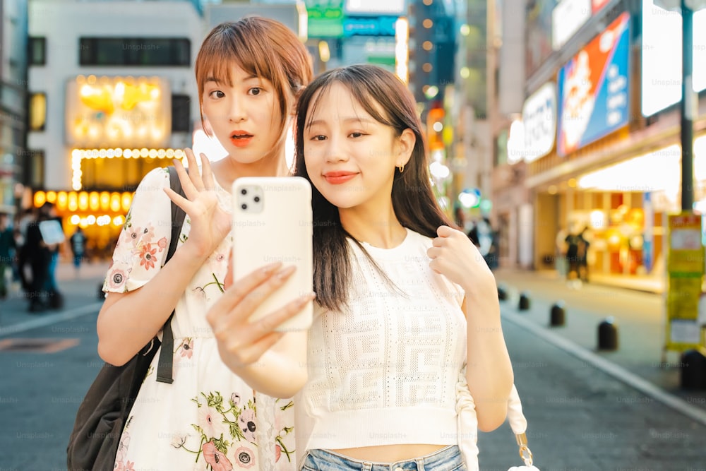 Mujeres jóvenes tomándose selfies en el centro de la ciudad