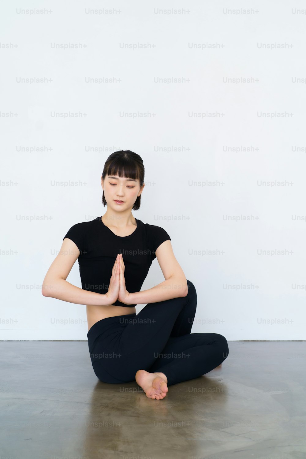Woman sitting and doing yoga indoors with black wear