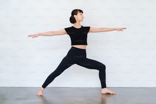 Junge Frau, die Yoga macht (Kriegerpose)