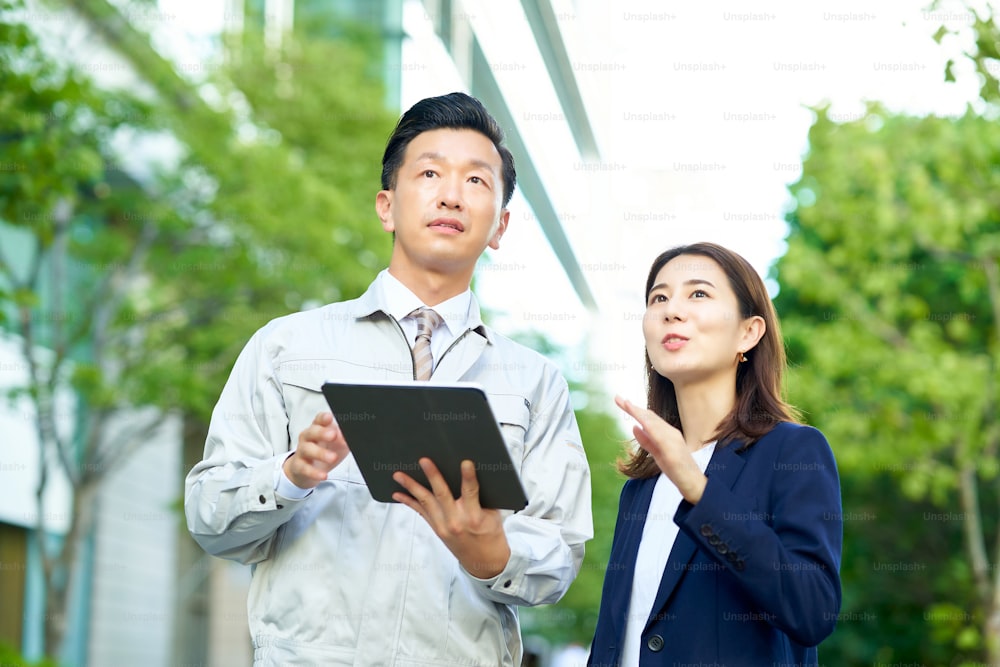 A man in work clothes and a woman in a suit outdoors