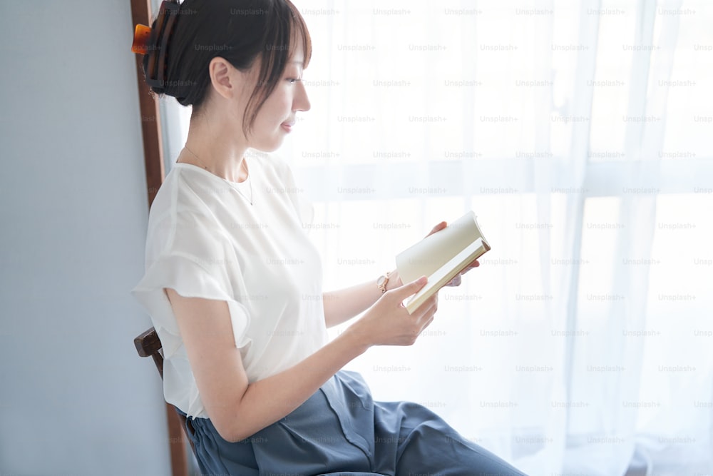 Giovane donna che legge un libro in casa