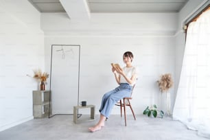 Une femme lisant un livre dans une pièce simple et lumineuse