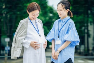 Business woman talking to a pregnant woman outdoors