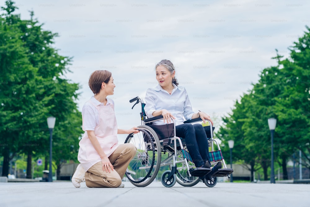 Uma mulher em uma cadeira de rodas e uma mulher em um avental cuidando dela